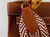 the brown and white handbag has a gold lock on it