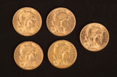 quatre pièces d'or de tailles et de formes différentes posées sur une surface noire