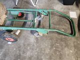a green hand truck with a wheel on the floor