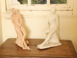 deux statues posées sur une table près d'une fenêtre