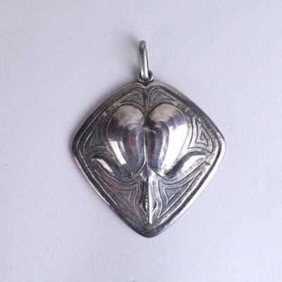 a silver pendant with a bird on it on a white surface