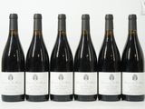 six bouteilles de vin sont alignées sur une surface blanche