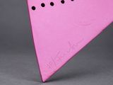 pink triangle shaped object with holes in the middle on a gray surface