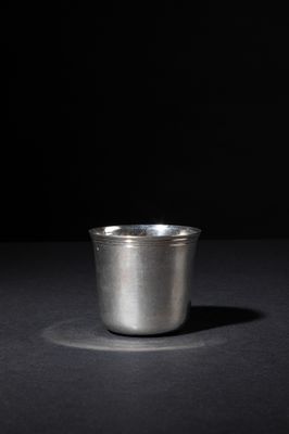 a silver cup sitting on top of a table next to a black background