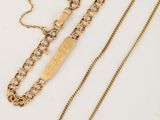deux chaînes en or et un collier en or posés sur une surface blanche