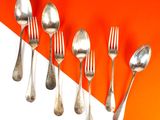 five silver spoons and two silver spoons on an orange and white background