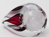 a red and white glass object on a white surface