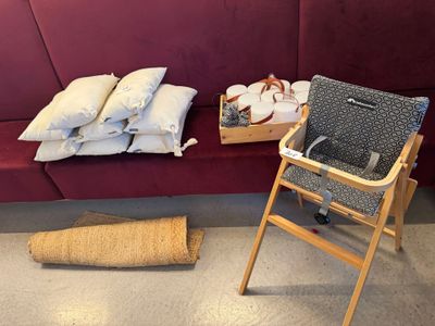 une chaise haute pour bébé à côté d'une pile d'oreillers posée par terre