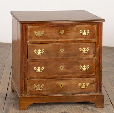 une commode ancienne en bois avec des poignées en laiton, posée sur un parquet