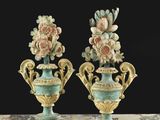 Deux vases remplis de fleurs sont posés sur une table, sur fond noir.