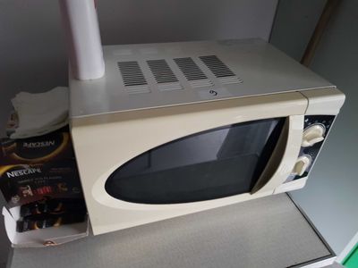 a microwave sitting on top of a counter next to a bottle of beer