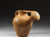 un vieux vase marron troué, posé sur une table