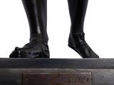 a bronze statue of a man standing on a platform