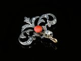 a close up of a red stone and diamond broochle