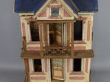 une maison de poupées avec un toit bleu et deux étages sur la façade