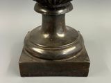 a silver vase with a flower on top of it