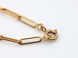 a close up of a gold chain bracelet on a white surface
