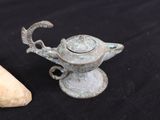 a small silver teapot next to a cork stopper on a black background