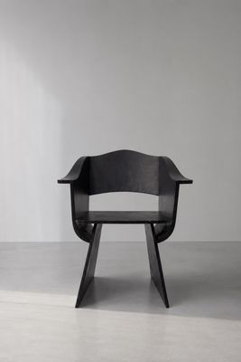 une chaise noire placée dans une pièce blanche, près d'un mur blanc