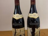 two bottles of wine sitting on top of a table next to each other