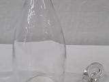 a clear glass bottle with a silver stopper next to it