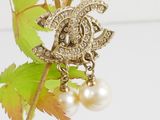 a close up of a brooch with pearls on a branch