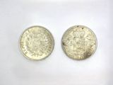 two silver coins are shown side by side on a white surface