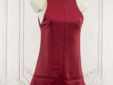 a red dress on a mannequin stand in front of a white wall