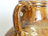 a brown vase sitting on a table with a white wall in the background