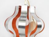 a silver and orange ornament hanging on a white wall