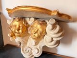 une sculpture dorée et blanche posée sur une étagère près d'un mur
