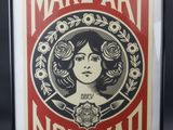 une personne brandissant une affiche sur laquelle on peut lire « Make art, not war »
