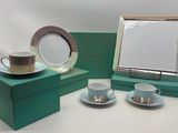 deux tasses et soucoupes posées sur une table, à côté d'un cadre photo