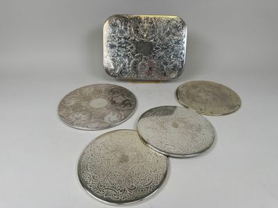 four silver coasters and a silver purse on a white surface