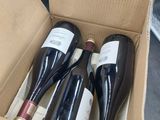 three bottles of wine in a cardboard box on the floor