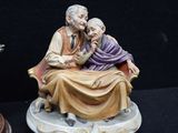 two figurines of a man and a woman sitting on a bench