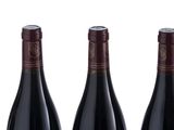 six bottles of wine are lined up on a white surface