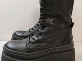 un gros plan sur une paire de bottes noires posées sur une surface blanche