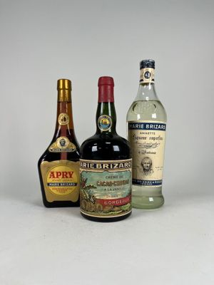 trois bouteilles d'alcool sont alignées sur une surface blanche