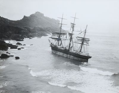 photographie en noir et blanc d'un navire en mer, près d'une côte rocheuse