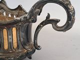 a silver bowl with a handle on a white surface