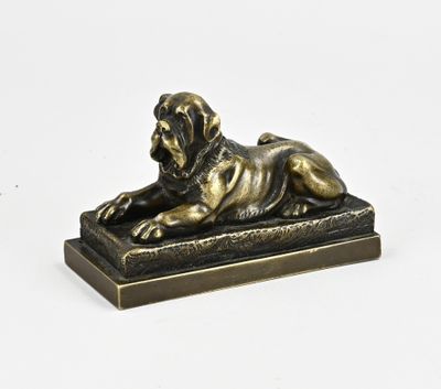 a bronze statue of a dog laying down on a wooden base