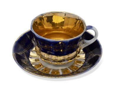 une tasse et une soucoupe bleues et dorées posées sur une soucoupe