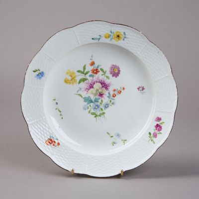 Assiette en porcelaine à décor peint de fleurs, l'aile imita…