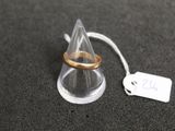 une bague en or posée sur un cône transparent, avec une étiquette de prix