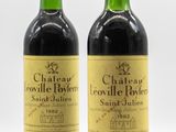 deux bouteilles de vin posées l'une à côté de l'autre sur une surface blanche