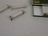 four pieces of metal on a white surface next to a box