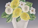 a ceramic vase with lemons and flowers in it