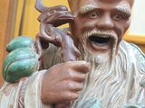 a statue of a man with a beard holding a frog