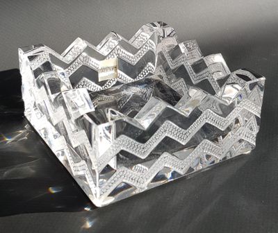 a clear glass ashtray on a table with a black background